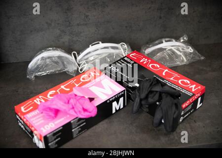 Hamburg, Germany. 27th Apr, 2020. Packs of pink and black disposable gloves and three plastic face masks are lying on a table in a hairdressing salon. The hairdressers had to close for six weeks because of the new corona virus, and now they are to be allowed to open again on 4 May. Credit: Christian Charisius/dpa/Alamy Live News Stock Photo