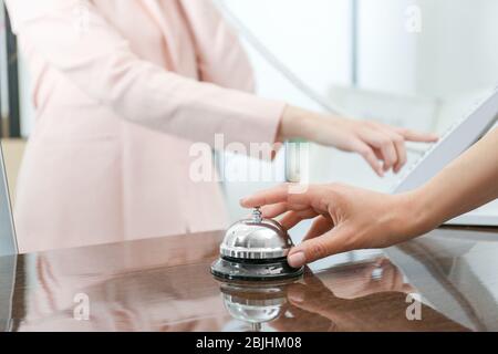 Woman ringing service bell in hotel lobby Stock Photo