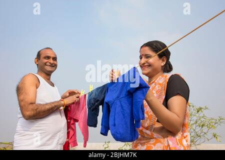 indian Couple drying clothes on clothesline Stock Photo