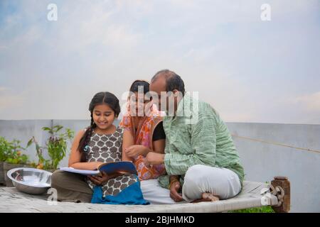 Indian mother and father helping daughters with homework Stock Photo