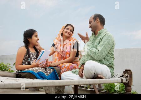 Indian mother and father helping daughters with homework Stock Photo