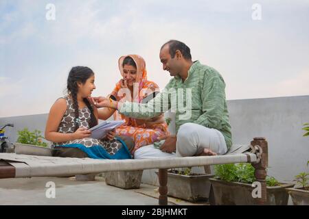 Indian mother and father helping daughters with homework Stock Photo