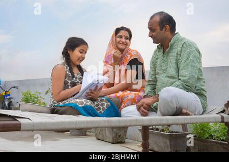 Indian mother and father helping daughters with homework Stock Photo