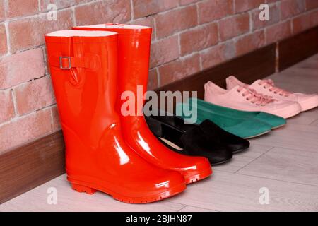 Different shoes near red brick wall in hallway Stock Photo - Alamy