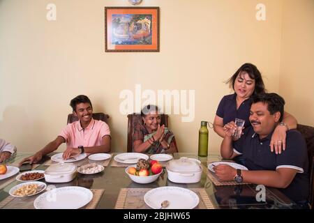 Happy family sitting around the dining table at home. Stock Photo