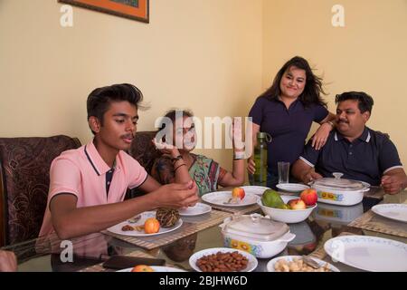 Happy family sitting around the dining table at home. Stock Photo
