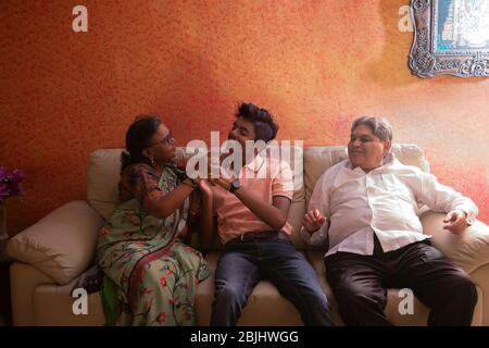 Grandson sitting on the sofa with grandparents. Stock Photo