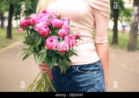 Young woman holding bouquet with beautiful peonies on street Stock Photo