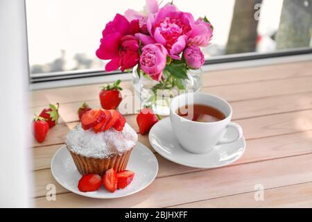 Delicious muffin and cup of tea on windowsill Stock Photo