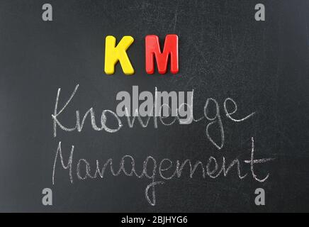 Phrase KNOWLEDGE MANAGEMENT written on blackboard. Management concept Stock Photo