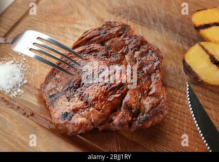 Delicious grilled steak on wooden board in restaurant Stock Photo