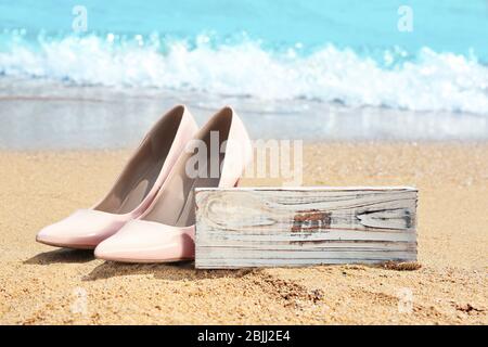 Beautiful high heel shoes and wooden board on seaside. Beach