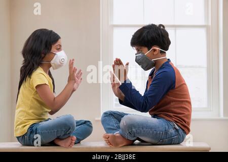 Siblings playing inside their home wearing masks due to terrible air pollution outside. (Children) Stock Photo