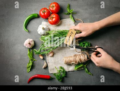 Female hands cutting thread and various fresh herbs on table Stock Photo