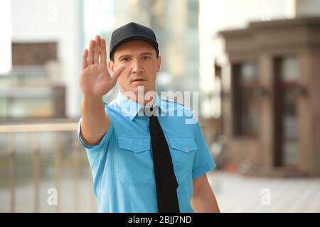 Male security guard showing stop gesture, outdoors Stock Photo