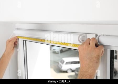 Young man installing window screens indoors Stock Photo