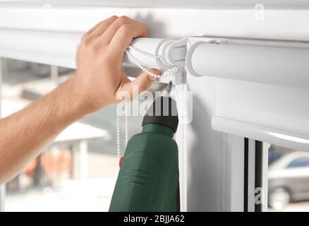 Young man installing window screens indoors Stock Photo