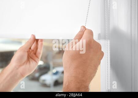 Young man installing window screens indoors Stock Photo