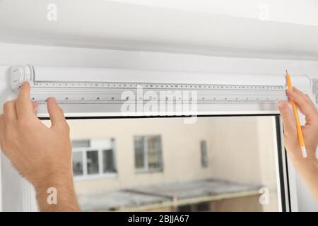 Young man installing window screens indoors Stock Photo