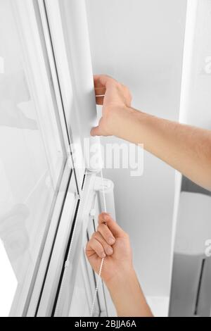 Young man installing window screens indoors Stock Photo
