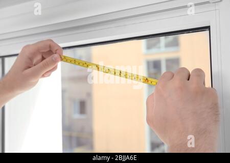 Young man installing window screens indoors Stock Photo