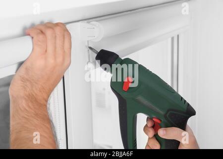 Young man installing window screens indoors Stock Photo