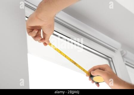 Young man installing window screens indoors Stock Photo