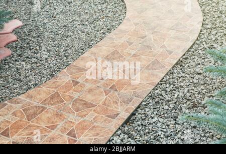 Pathway made from ceramic tiles with crushed stone in garden Stock Photo
