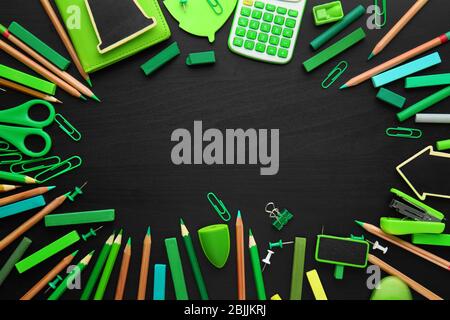 Frame of green office supplies on black wooden background Stock Photo
