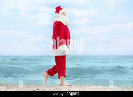 Authentic Santa Claus walking on beach Stock Photo