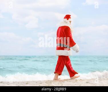 Authentic Santa Claus walking on beach Stock Photo