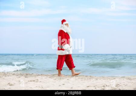 Authentic Santa Claus walking on beach Stock Photo