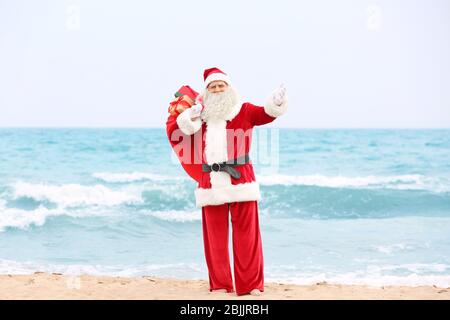 Authentic Santa Claus with big red bag full of gifts on beach Stock ...