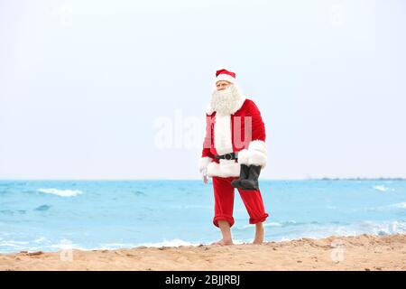 Authentic Santa Claus walking on beach Stock Photo