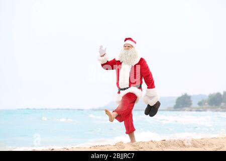 Authentic Santa Claus walking on beach Stock Photo