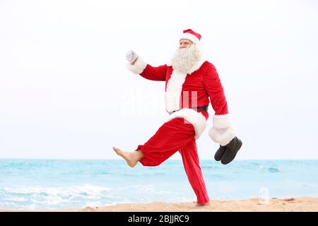 Authentic Santa Claus walking on beach Stock Photo