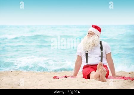 Authentic Santa Claus sitting on beach Stock Photo