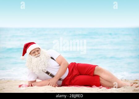 Authentic Santa Claus lying on beach Stock Photo