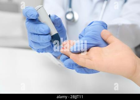 Doctor in latex gloves taking sample of patient's blood using lancet pen. Diabetes concept Stock Photo
