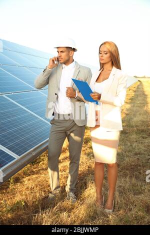 Engineers discussing project on installation of solar panels outdoors Stock Photo