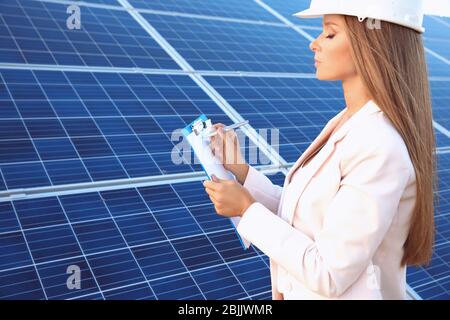 Female engineer developing project on installation of solar panels outdoors Stock Photo