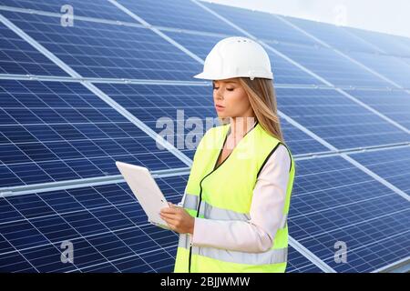Female engineer developing project on installation of solar panels outdoors Stock Photo