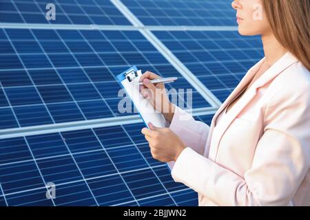 Female engineer developing project on installation of solar panels outdoors Stock Photo