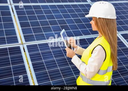 Female engineer developing project on installation of solar panels outdoors Stock Photo