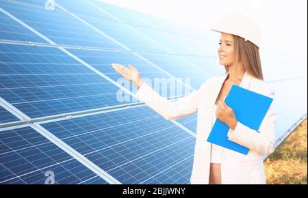 Female engineer developing project on installation of solar panels outdoors Stock Photo
