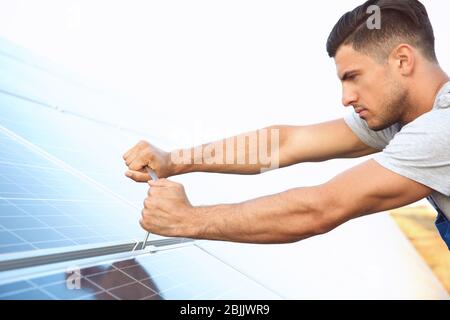 Young worker installing solar panels outdoors Stock Photo