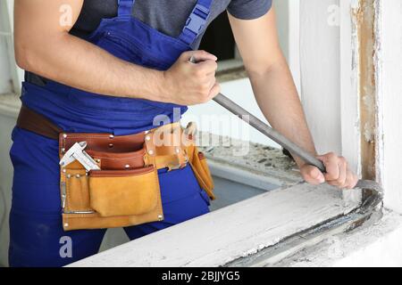 Worker repairing window in flat Stock Photo
