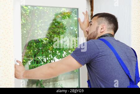 Worker repairing window in flat Stock Photo