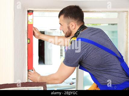 Worker repairing window in flat Stock Photo