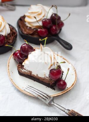 Mini tarts in iron skillets with oreo cookie dough, chocolate filling, whipped cream and fresh berries. Stock Photo